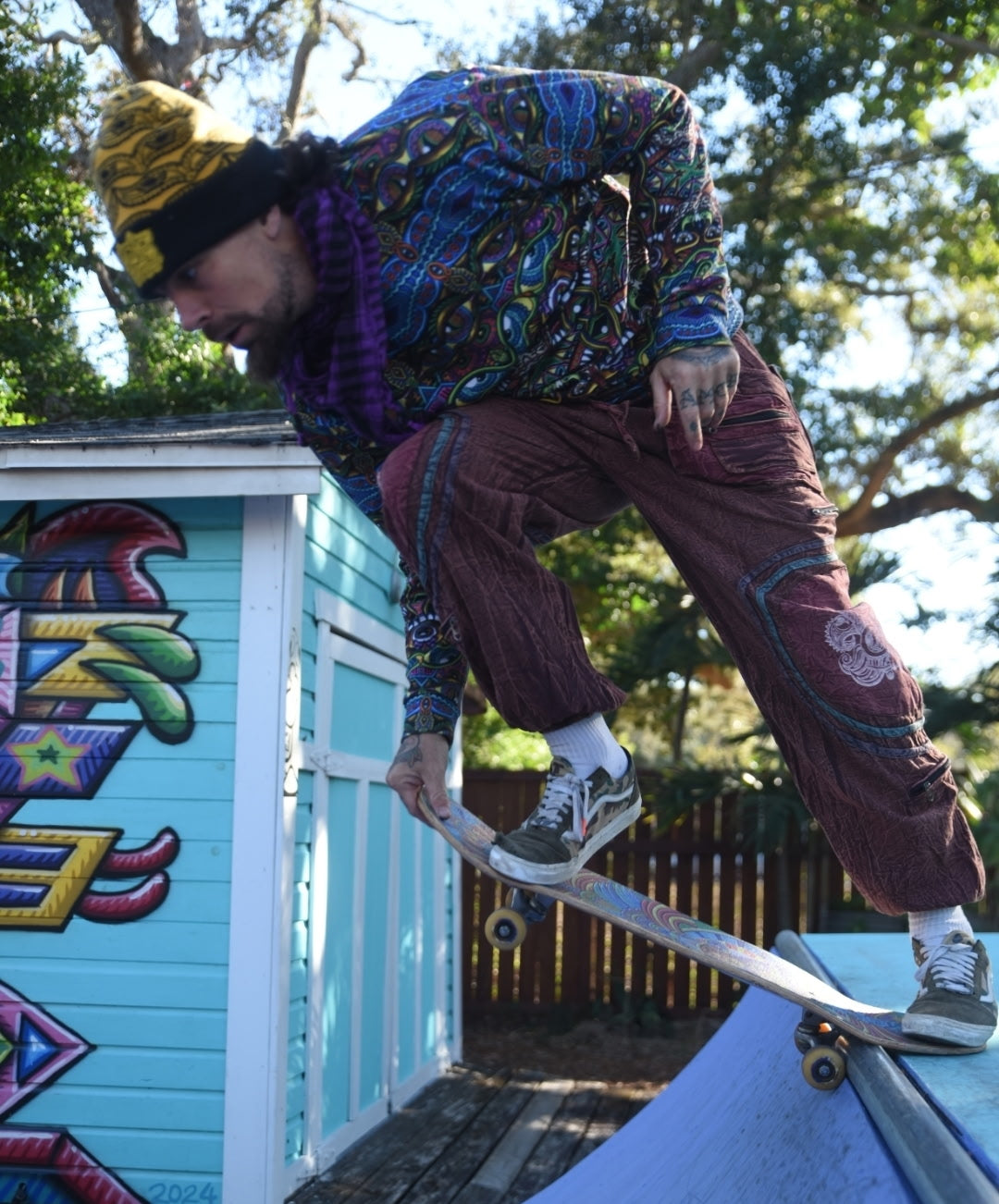 Skateboarder wearing handmade burgundy Chris Dyer Dyer-Jawnz parachute pants while performing a trick on a ramp.