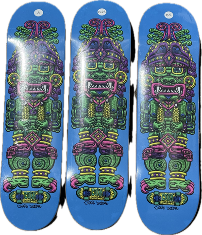 A skateboard deck with a vibrant blue background featuring Chris Dyer’s colorful psychedelic depiction of Wiracocha, the Incan Corn God, in green, purple, and pink.