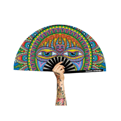 A tattooed hand holds the Festival Folding Fan – Light Worker & Taita Inti, featuring a psychedelic sun face and vivid blue, orange, green, and pink patterns in a vibrant composition.