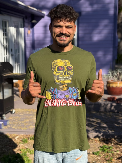 Man wearing a green t-shirt with a colorful graphic design, giving a thumbs-up gesture outdoors.