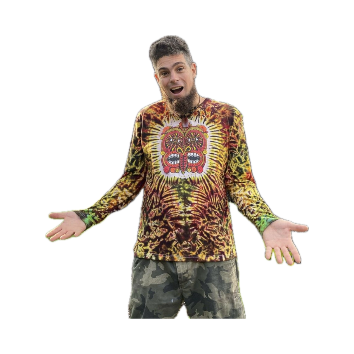 Man with short hair and beard in a colorful Lava Flow Tribal Mask Tie Dye Long Sleeve T Shirt and camouflage pants stands outdoors by tree trunks, arms outstretched, wearing a surprised expression.